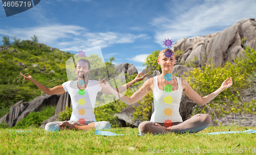 Image of couple doing yoga in lotus pose with seven chakras