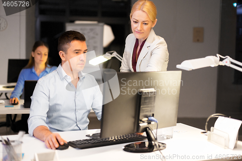 Image of business team with computer working late at office