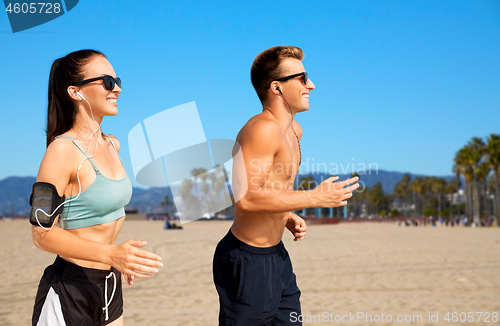 Image of couple with phones and arm bands running on beach