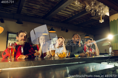 Image of Sport fans cheering at bar, pub and drinking beer while championship, competition is going