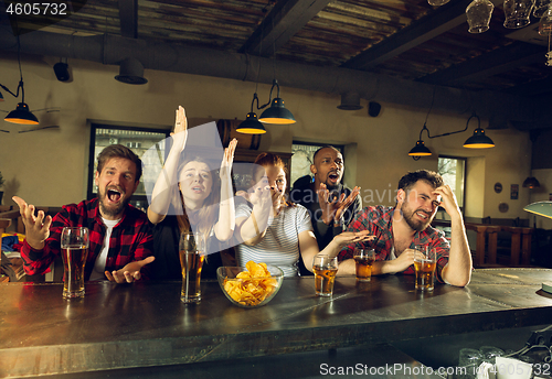 Image of Sport fans cheering at bar, pub and drinking beer while championship, competition is going