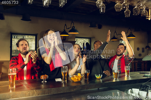 Image of Sport fans cheering at bar, pub and drinking beer while championship, competition is going