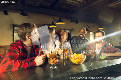 Image of Sport fans cheering at bar, pub and drinking beer while championship, competition is going