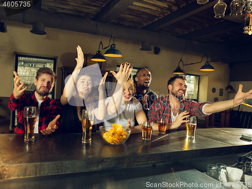Image of Sport fans cheering at bar, pub and drinking beer while championship, competition is going