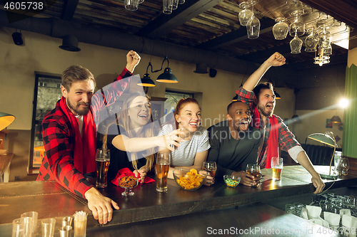 Image of Sport fans cheering at bar, pub and drinking beer while championship, competition is going