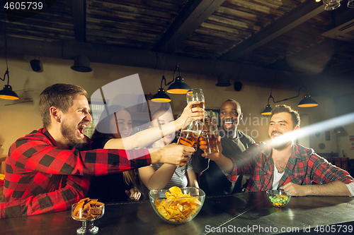 Image of Sport fans cheering at bar, pub and drinking beer while championship, competition is going