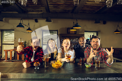 Image of Sport fans cheering at bar, pub and drinking beer while championship, competition is going