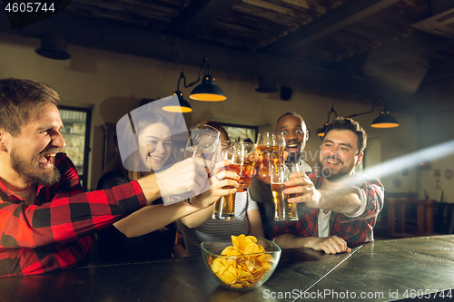 Image of Sport fans cheering at bar, pub and drinking beer while championship, competition is going