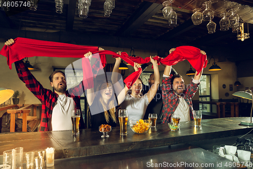 Image of Sport fans cheering at bar, pub and drinking beer while championship, competition is going