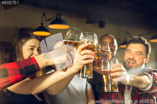Image of Sport fans cheering at bar, pub and drinking beer while championship, competition is going