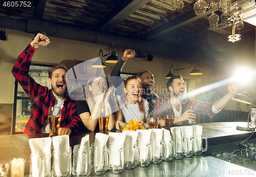 Image of Sport fans cheering at bar, pub and drinking beer while championship, competition is going