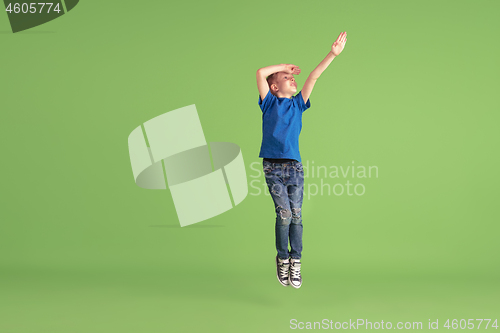 Image of Happy boy playing and having fun on green studio background, emotions