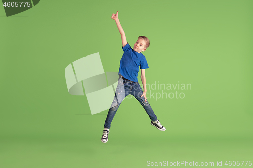 Image of Happy boy playing and having fun on green studio background, emotions