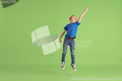 Image of Happy boy playing and having fun on green studio background, emotions