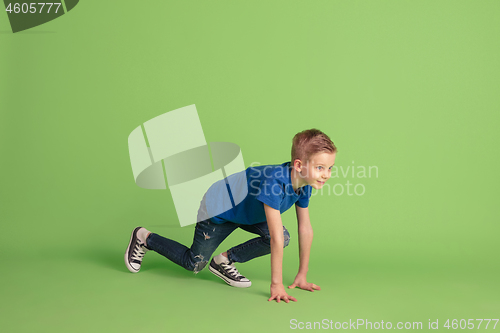 Image of Happy boy playing and having fun on green studio background, emotions