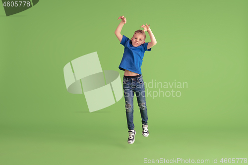 Image of Happy boy playing and having fun on green studio background, emotions