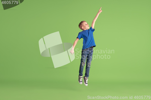 Image of Happy boy playing and having fun on green studio background, emotions