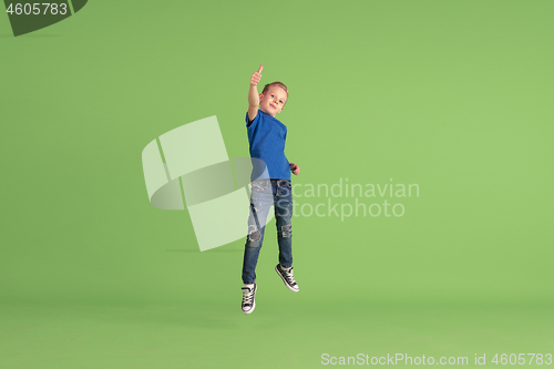 Image of Happy boy playing and having fun on green studio background, emotions