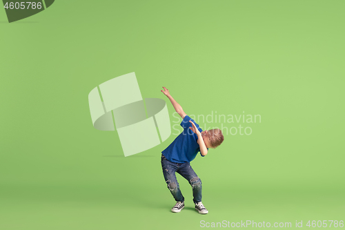 Image of Happy boy playing and having fun on green studio background, emotions