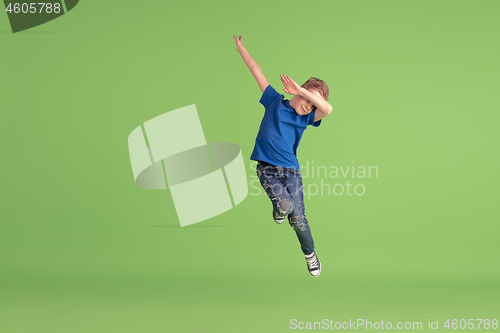 Image of Happy boy playing and having fun on green studio background, emotions