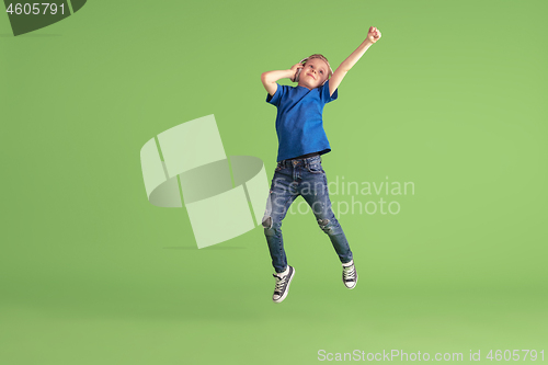 Image of Happy boy playing and having fun on green studio background, emotions