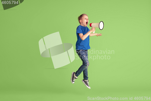 Image of Happy boy playing and having fun on green studio background, emotions