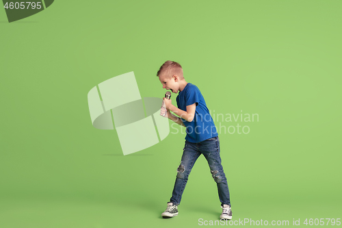 Image of Happy boy playing and having fun on green studio background, emotions