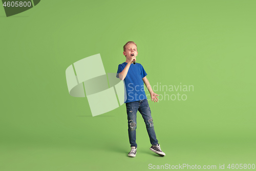 Image of Happy boy playing and having fun on green studio background, emotions