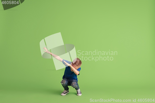 Image of Happy boy playing and having fun on green studio background, emotions