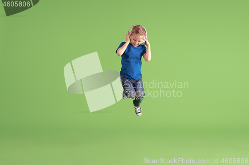 Image of Happy boy playing and having fun on green studio background, emotions