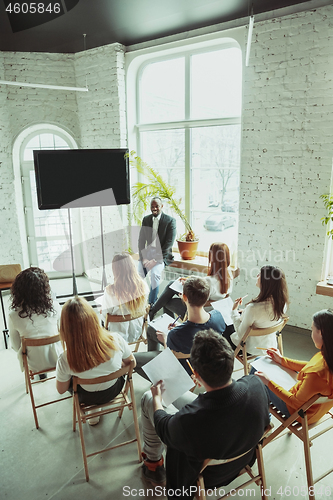 Image of Male african-american speaker giving presentation in hall at university workshop