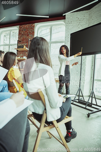 Image of Female african-american speaker giving presentation in hall at university workshop