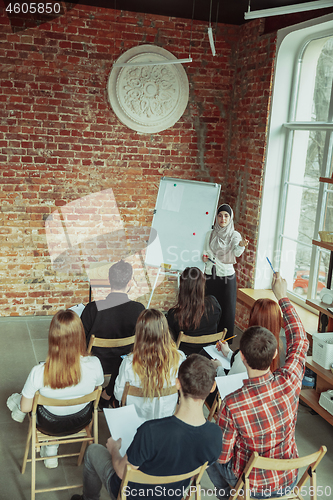 Image of Female muslim speaker giving presentation in hall at university workshop