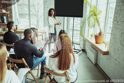 Image of Female african-american speaker giving presentation in hall at university workshop