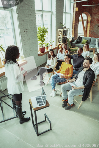 Image of Female african-american speaker giving presentation in hall at university workshop