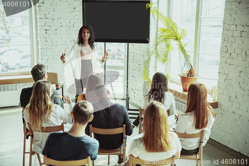 Image of Female african-american speaker giving presentation in hall at university workshop