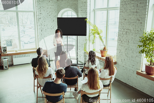 Image of Female african-american speaker giving presentation in hall at university workshop