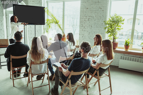 Image of Female african-american speaker giving presentation in hall at university workshop