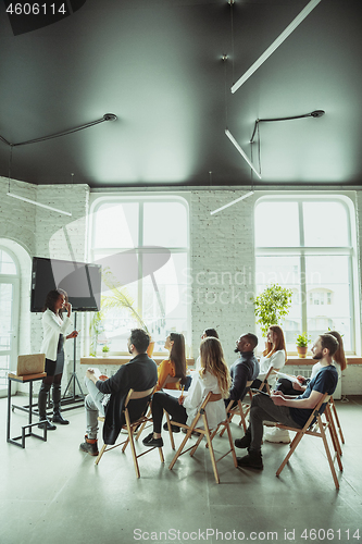 Image of Female african-american speaker giving presentation in hall at university workshop