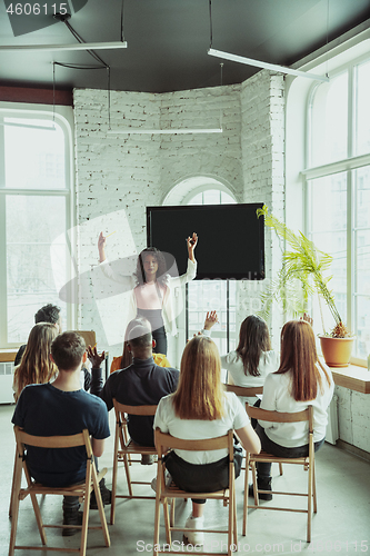 Image of Female african-american speaker giving presentation in hall at university workshop