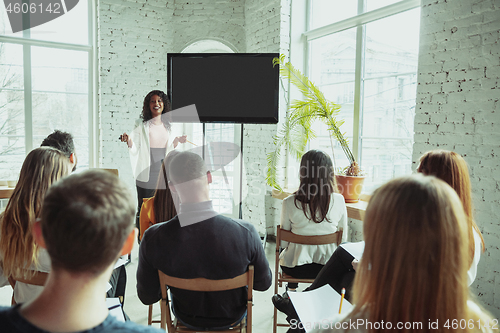 Image of Female african-american speaker giving presentation in hall at university workshop