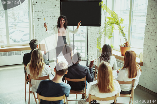 Image of Female african-american speaker giving presentation in hall at university workshop