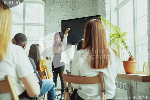 Image of Female african-american speaker giving presentation in hall at university workshop