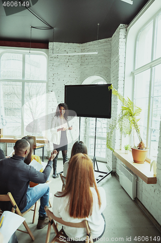 Image of Female african-american speaker giving presentation in hall at university workshop