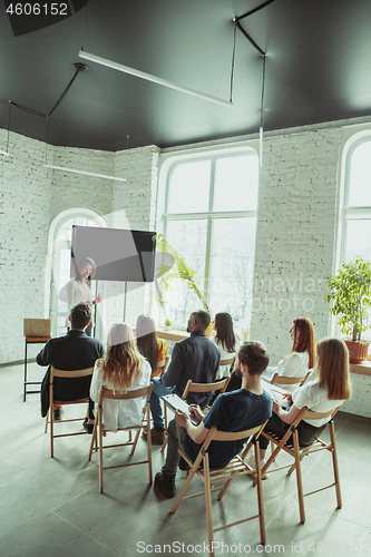 Image of Female african-american speaker giving presentation in hall at university workshop