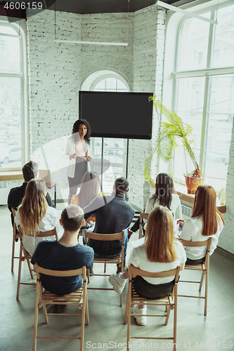 Image of Female african-american speaker giving presentation in hall at university workshop