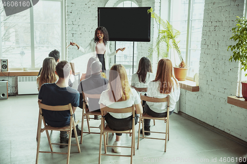 Image of Female african-american speaker giving presentation in hall at university workshop