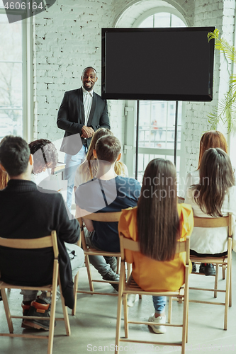 Image of Male african-american speaker giving presentation in hall at university workshop