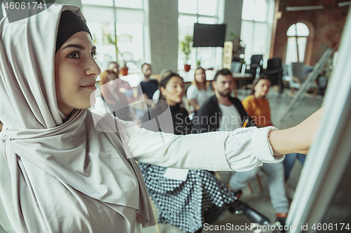 Image of Female muslim speaker giving presentation in hall at university workshop