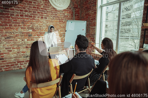 Image of Female muslim speaker giving presentation in hall at university workshop